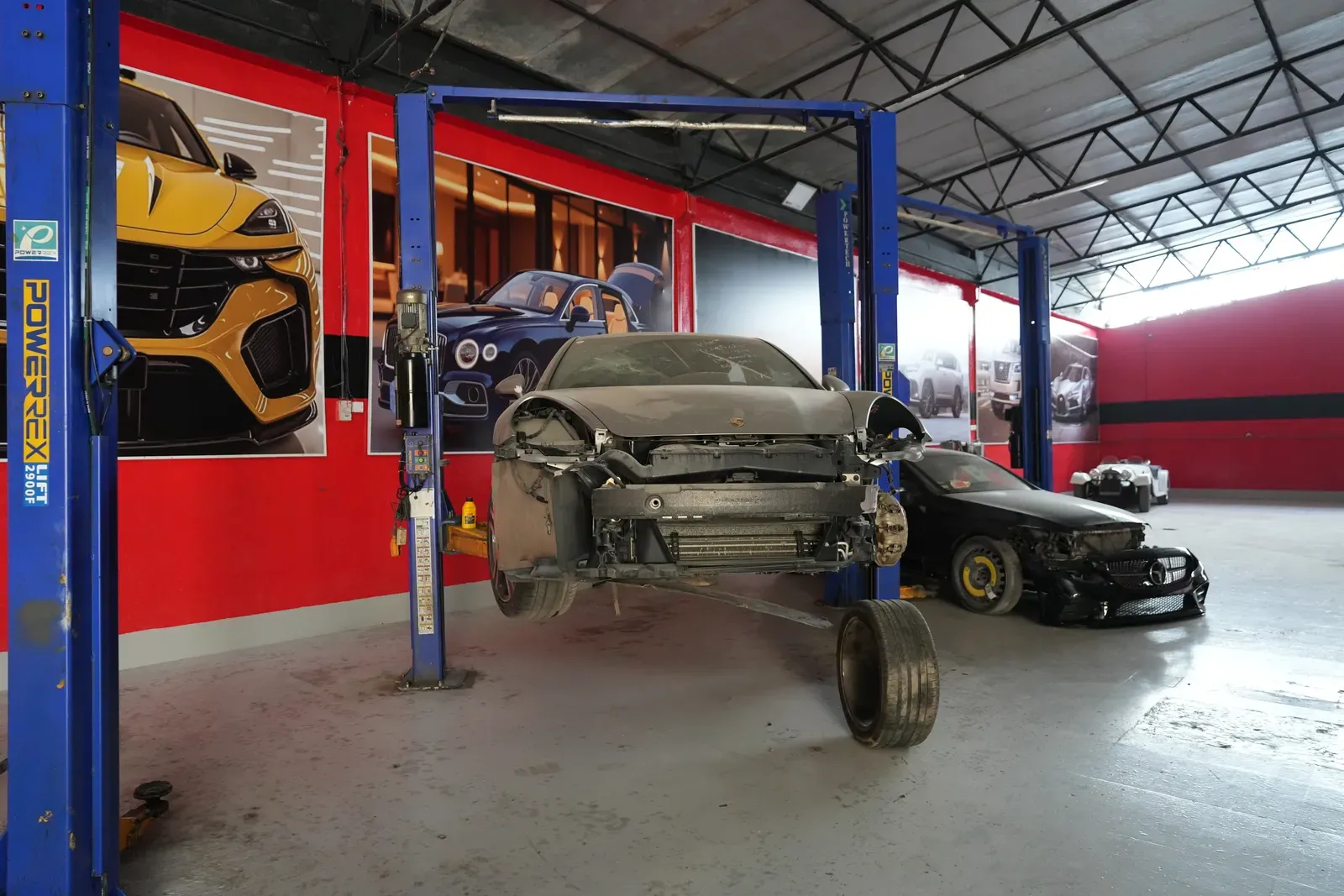 A car raised on a lift with its front end stripped down.