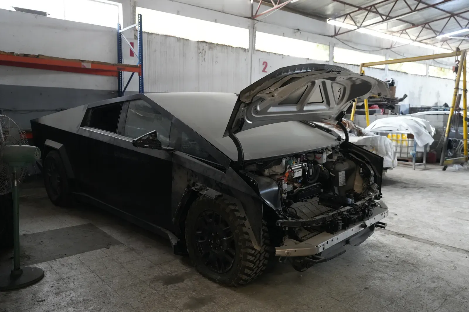 A black pick-up with the bonnet up and the front end stripped for work.