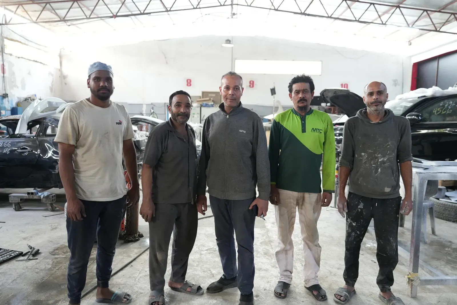 Five technicians standing together on the workshop floor in Sharjah.
