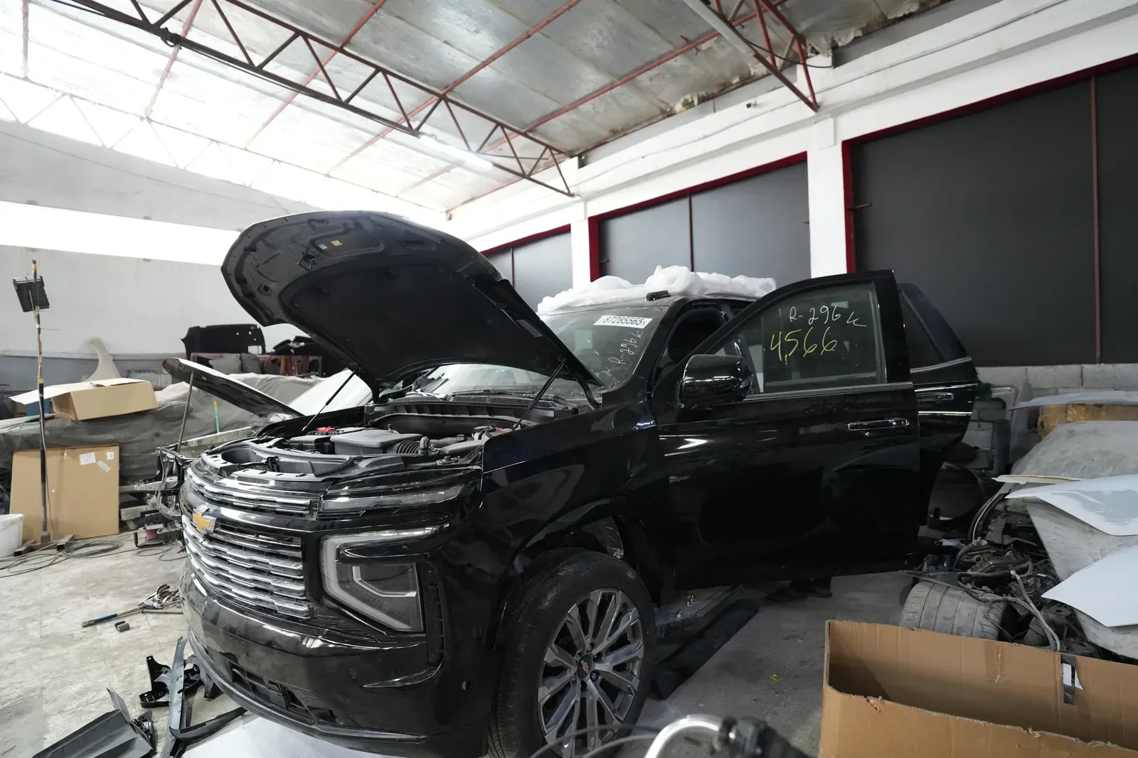 A black SUV in the body shop with the bonnet up.
