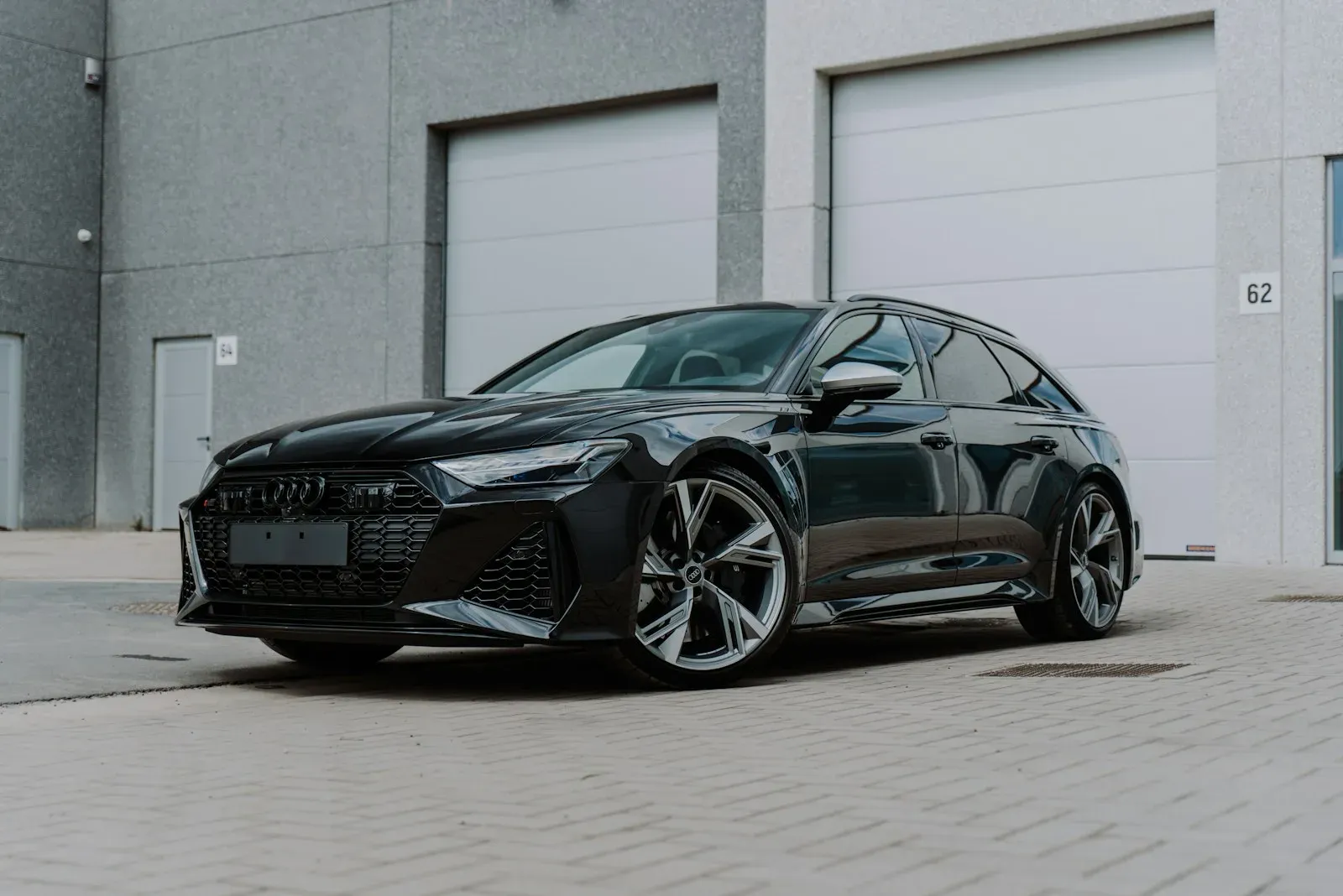 A black Audi RS 6 Avant parked in front of plain industrial doors.