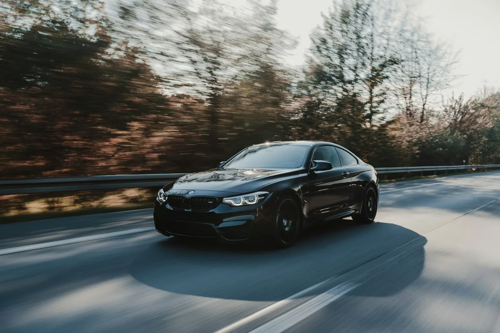 A black BMW M4 photographed in motion on an open road.