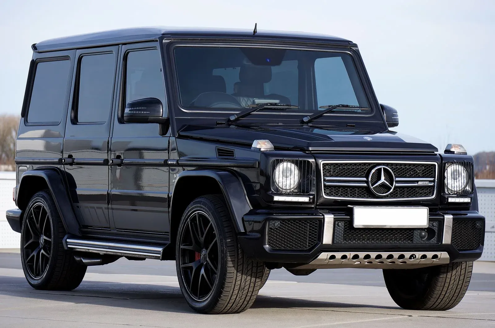 A black Mercedes-AMG G 63 photographed front three-quarter under an overcast sky.